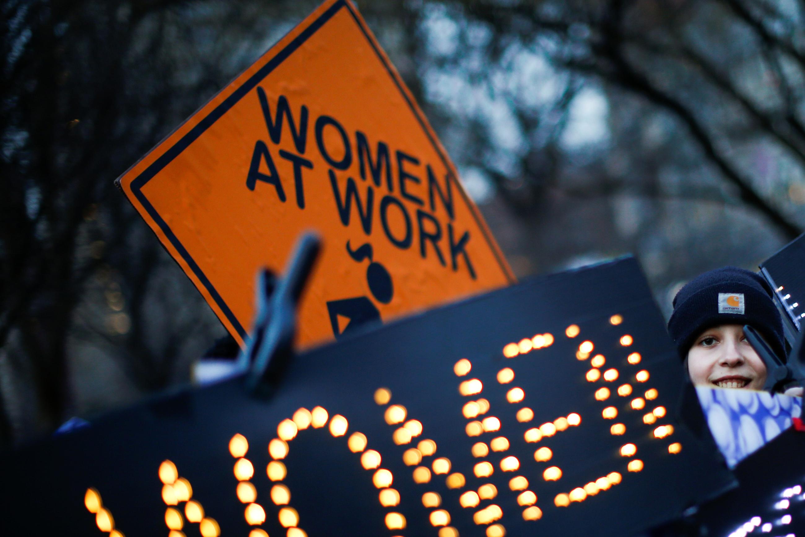 A woman holds signs as she attends a rally to commemorate International Women's Day at Union Square Park.