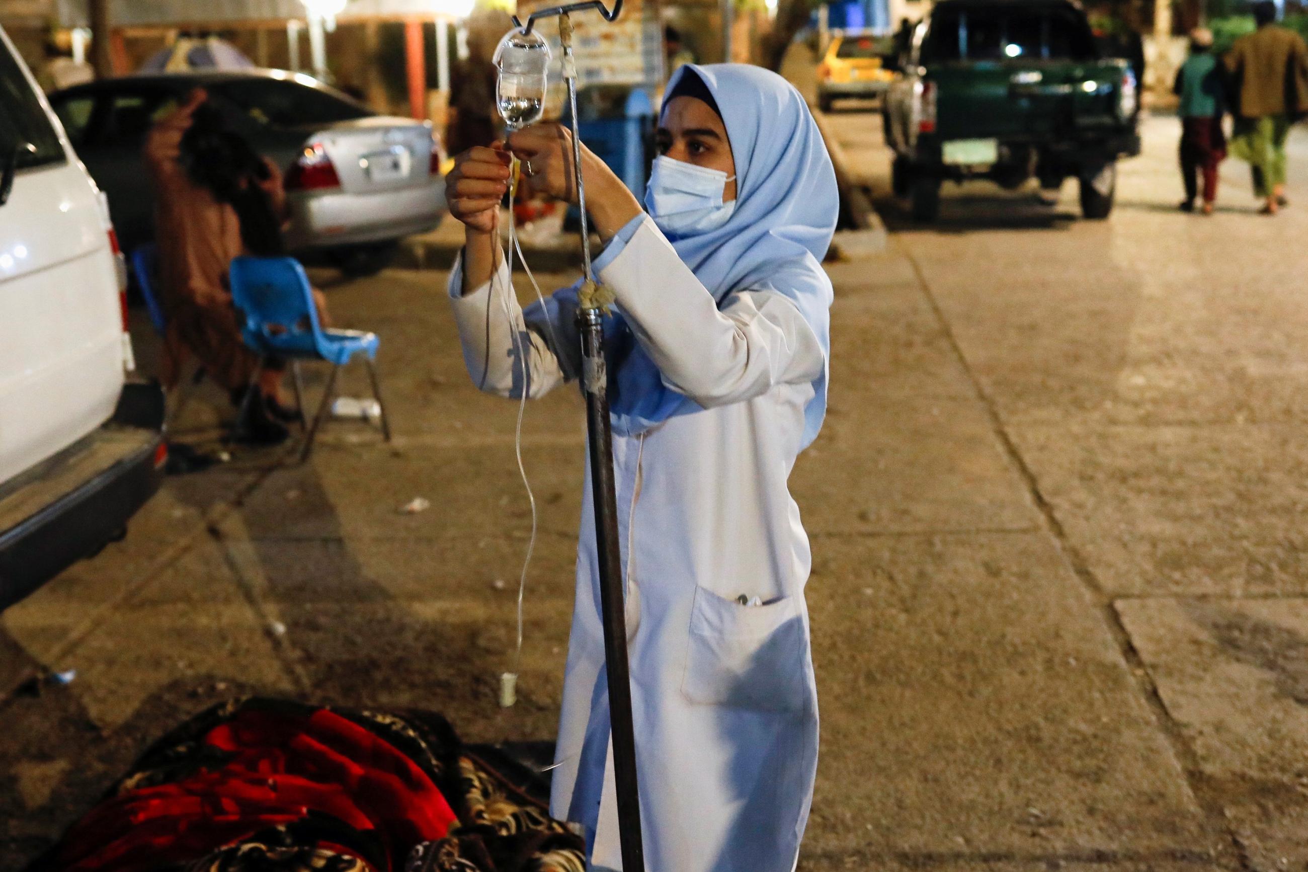 An Afghan nurse prepares serum drops for a victim of an earthquake in a hospital.