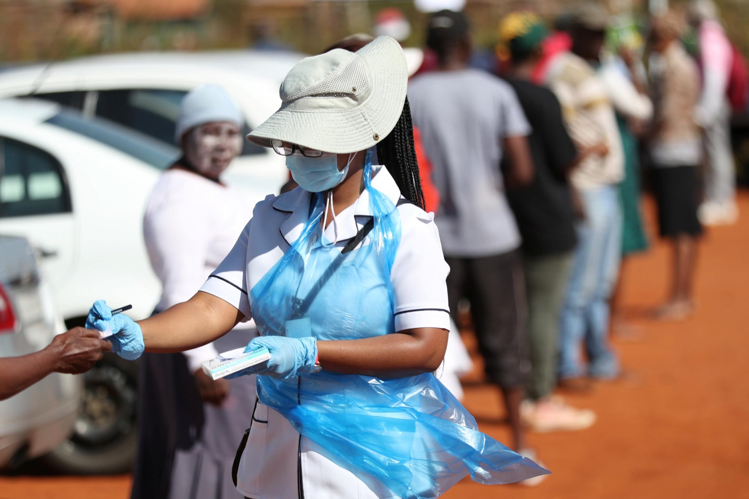 A member of medical staff attends to residents as they queue during screening and testing campaign aimed to combat the spread of COVID-19, in Lenasia, South Africa, on April 21, 2020.