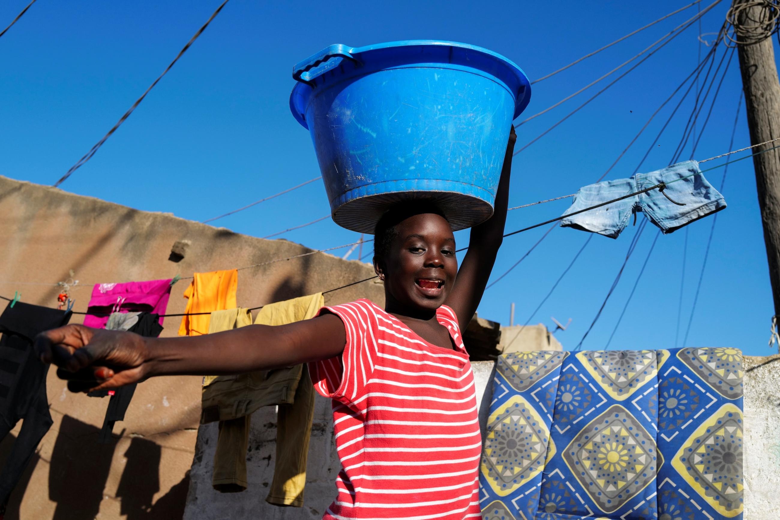 A girl carries a bucket with laundry on her head while heading home as the spread of the coronavirus disease continues, in Yoff neighbourhood, Dakar, Senegal on January 26, 2021.