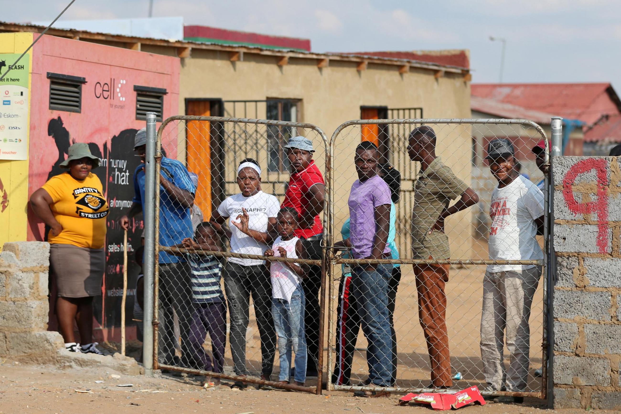 Residents look from behind a closed gate as members of the military patrol during a nationwide lockdown aimed at limiting the spread of novel coronavirus. Soweto, South Africa; April 23, 2020