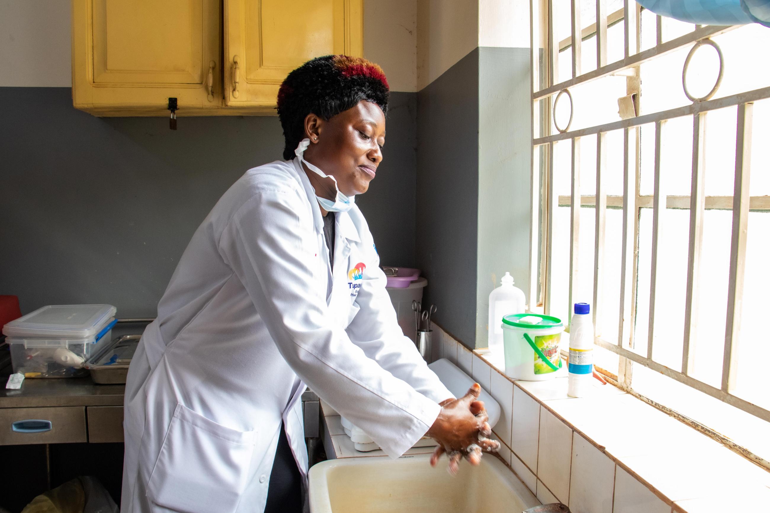 Ddungu Annet, a 39-year-old nursing officer, washes her hands in the labor ward before examining an expectant mother at Nabweru Health Center, Uganda. 