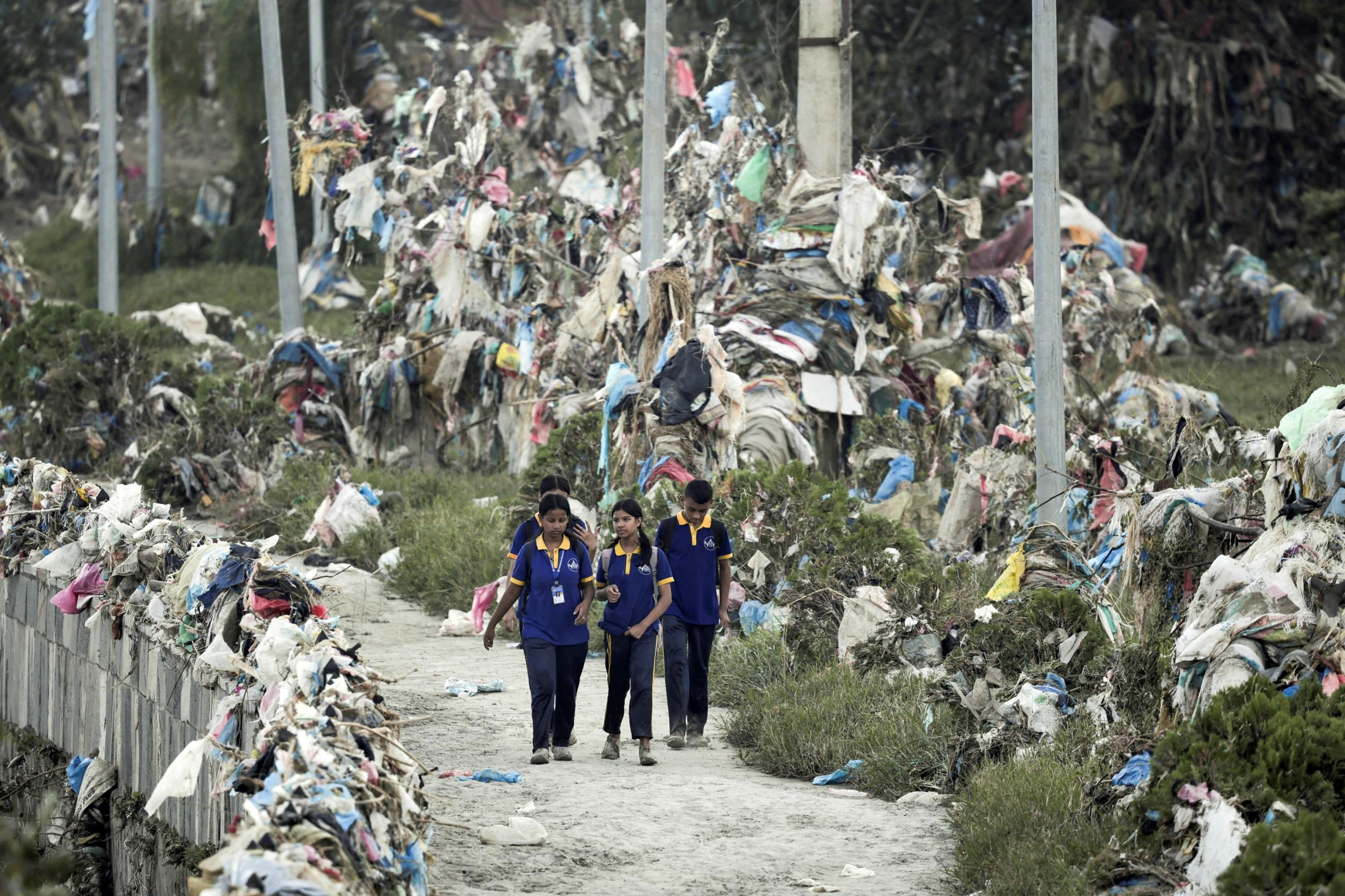 Students walk past the debris, mostly plastic waste dumped into the river by the people, as the flood water recedes from the bank of Bagmati river following the deadly flood due to heavy rains, in Kathmandu, Nepal, October 2, 2024. 