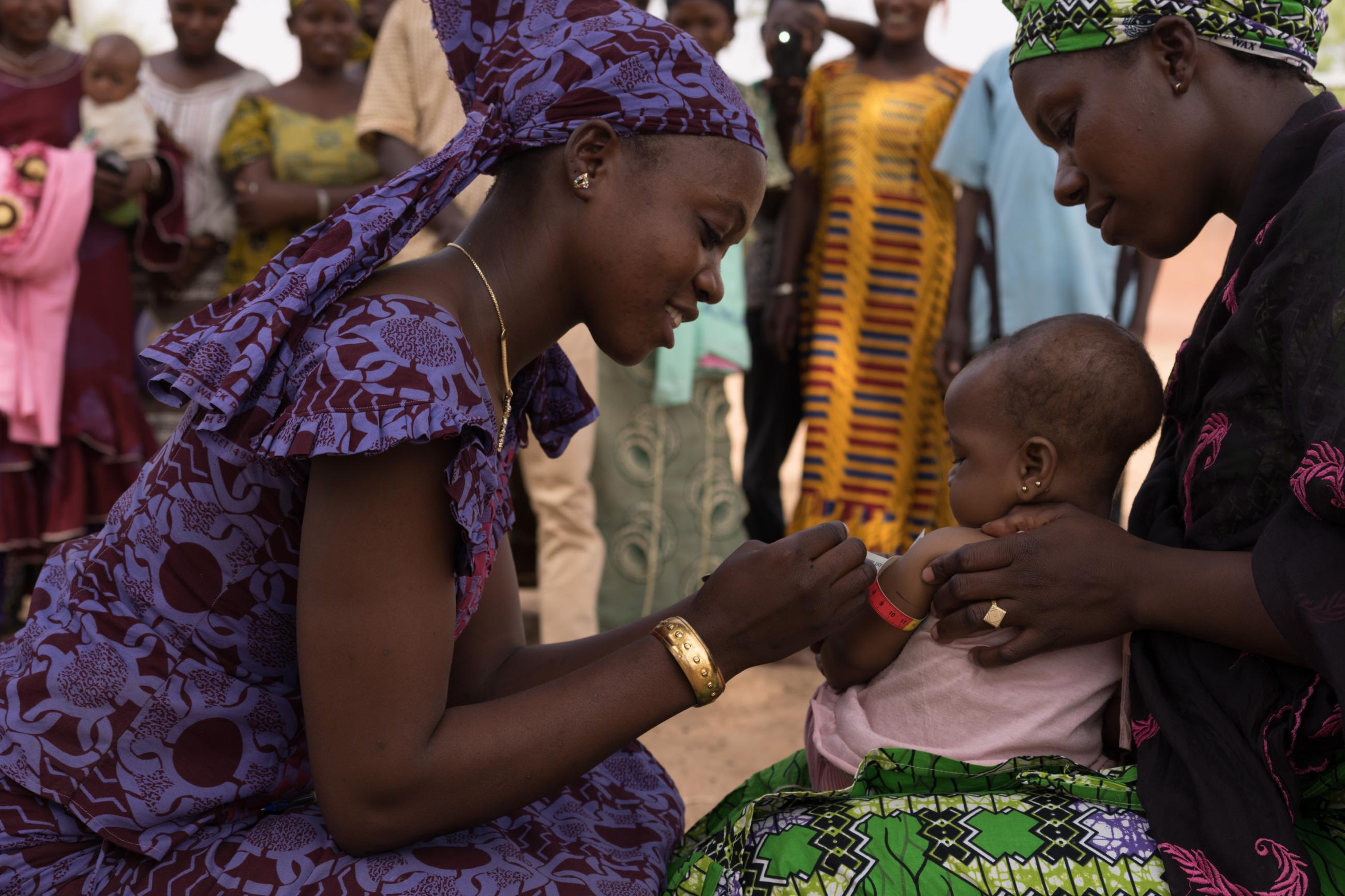 A community health worker evaluates a baby for malnutrition.