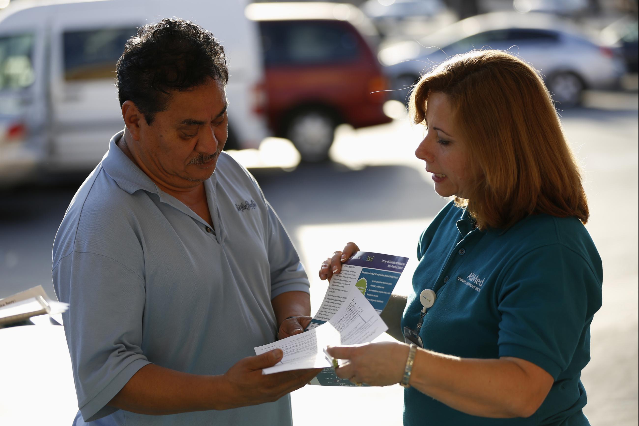 A patient care coordinator at AltaMed, speaks to a man during a community outreach on Obamacare.