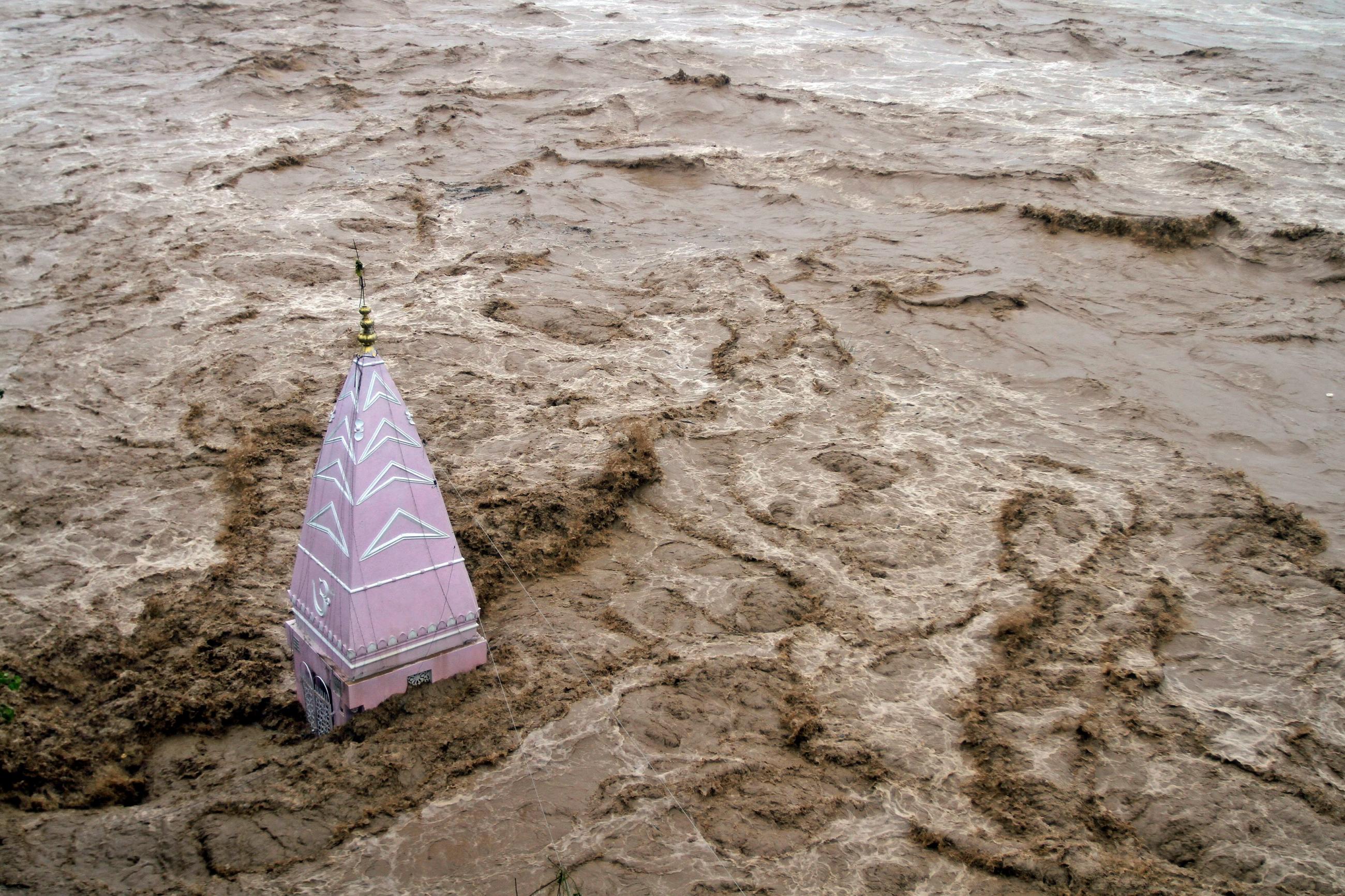 A temple stands amid the waters of the overflowing river Tawi during heavy rains in Jammu September 6, 2014. 