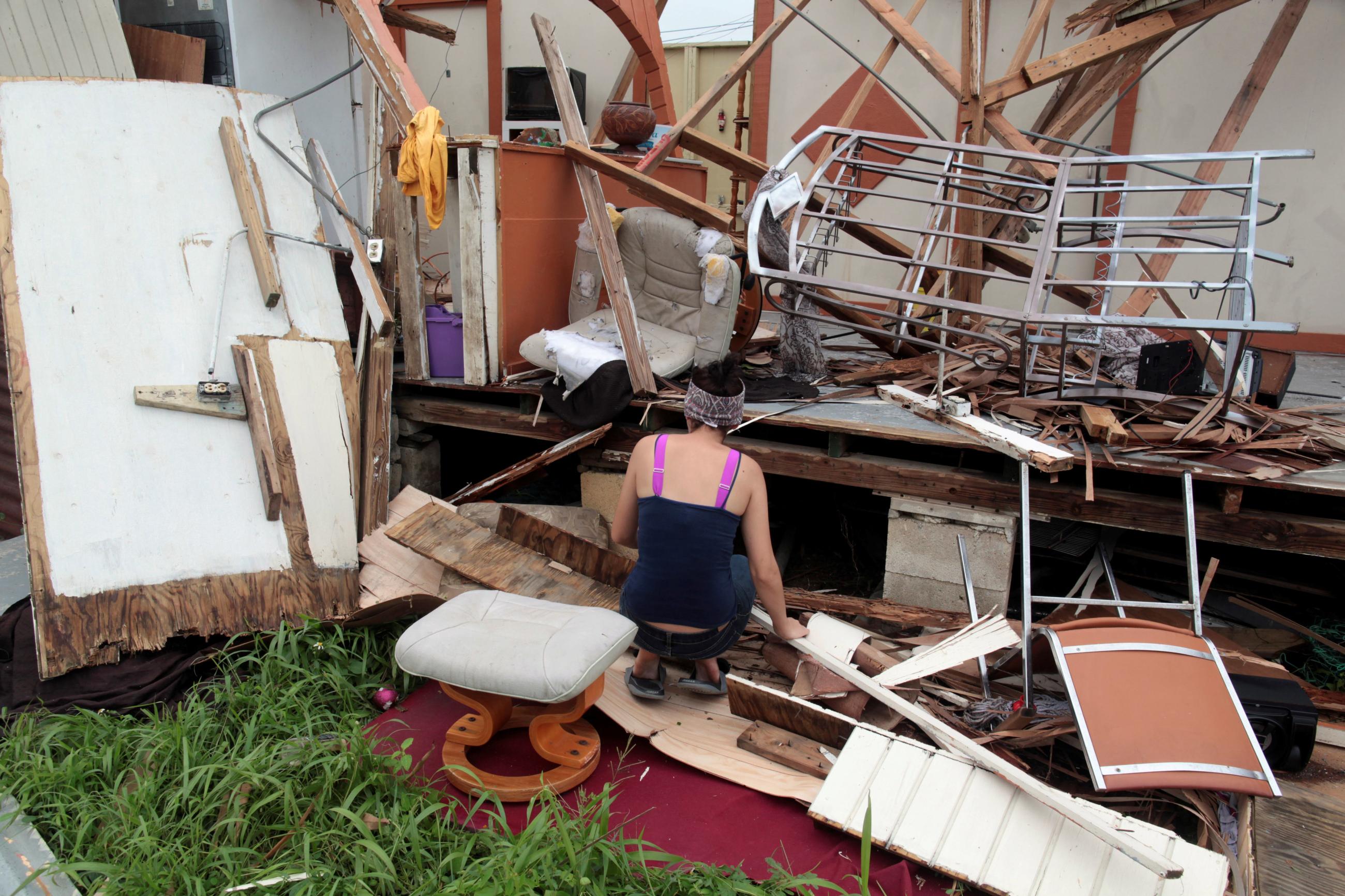 A woman kneels in front of the remains of her home after the area was hit by Hurricane Maria.