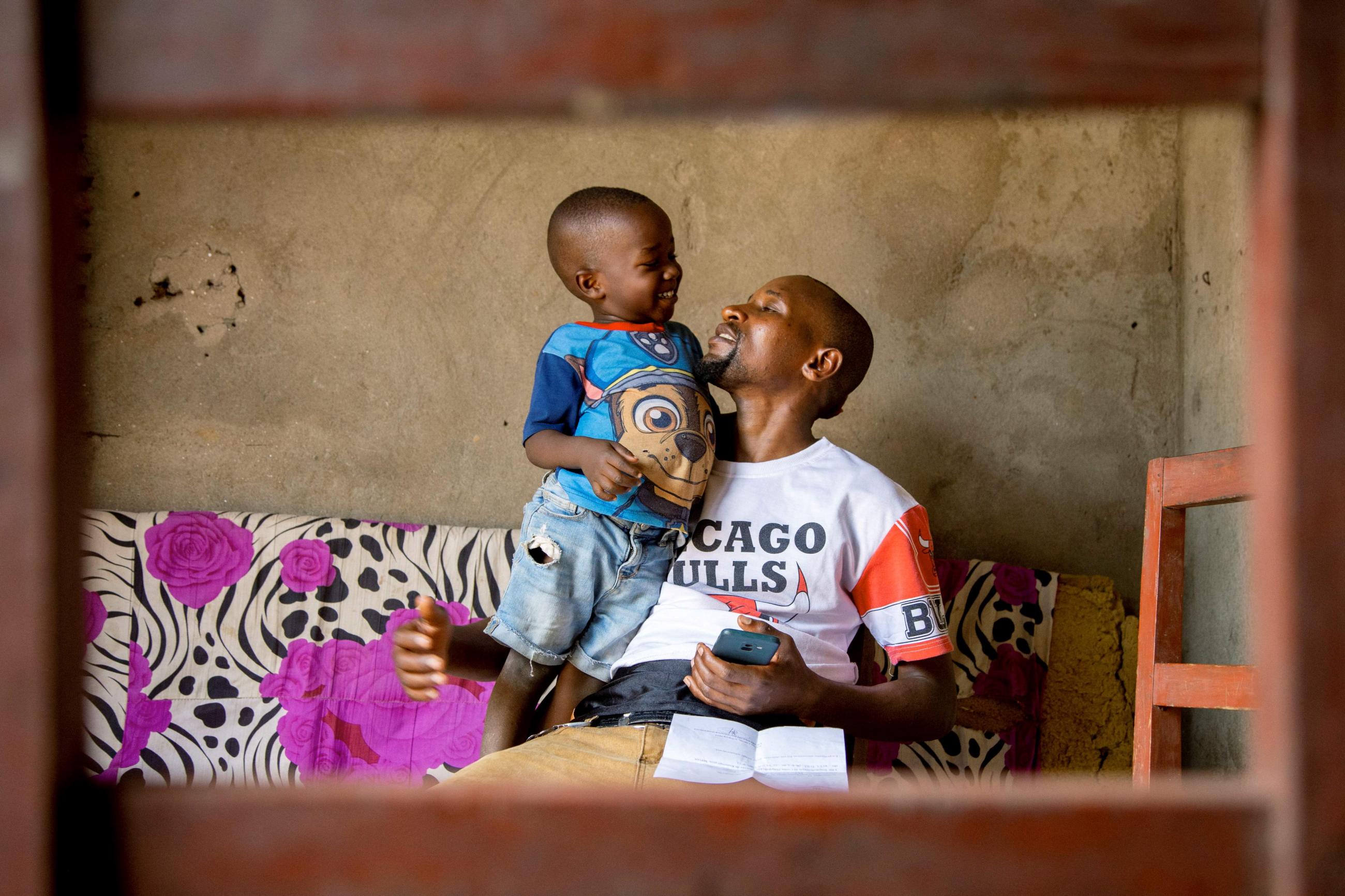 Manigaba Eric, plays with his son in their home after returning from the mpox treatment center.