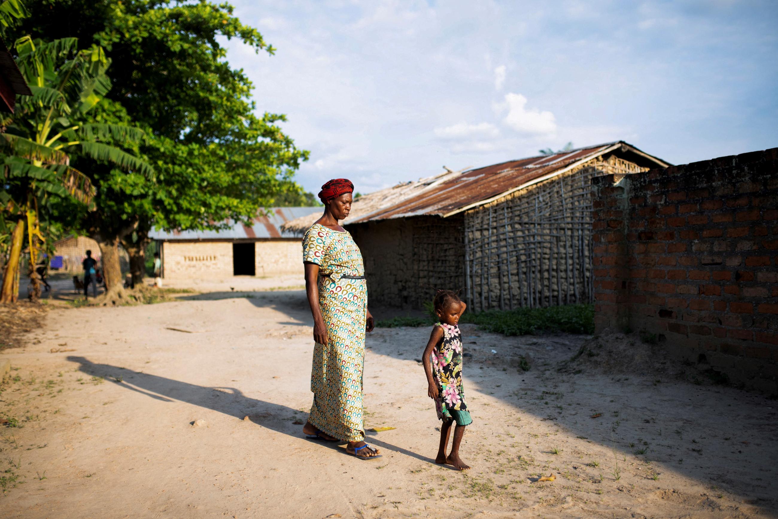 A woman walks her granddaughter to the restroom after having samples collected, at the Yalolia health center, in Yakusu, Tshopo, Democratic Republic of Congo, on October 3, 2022.
