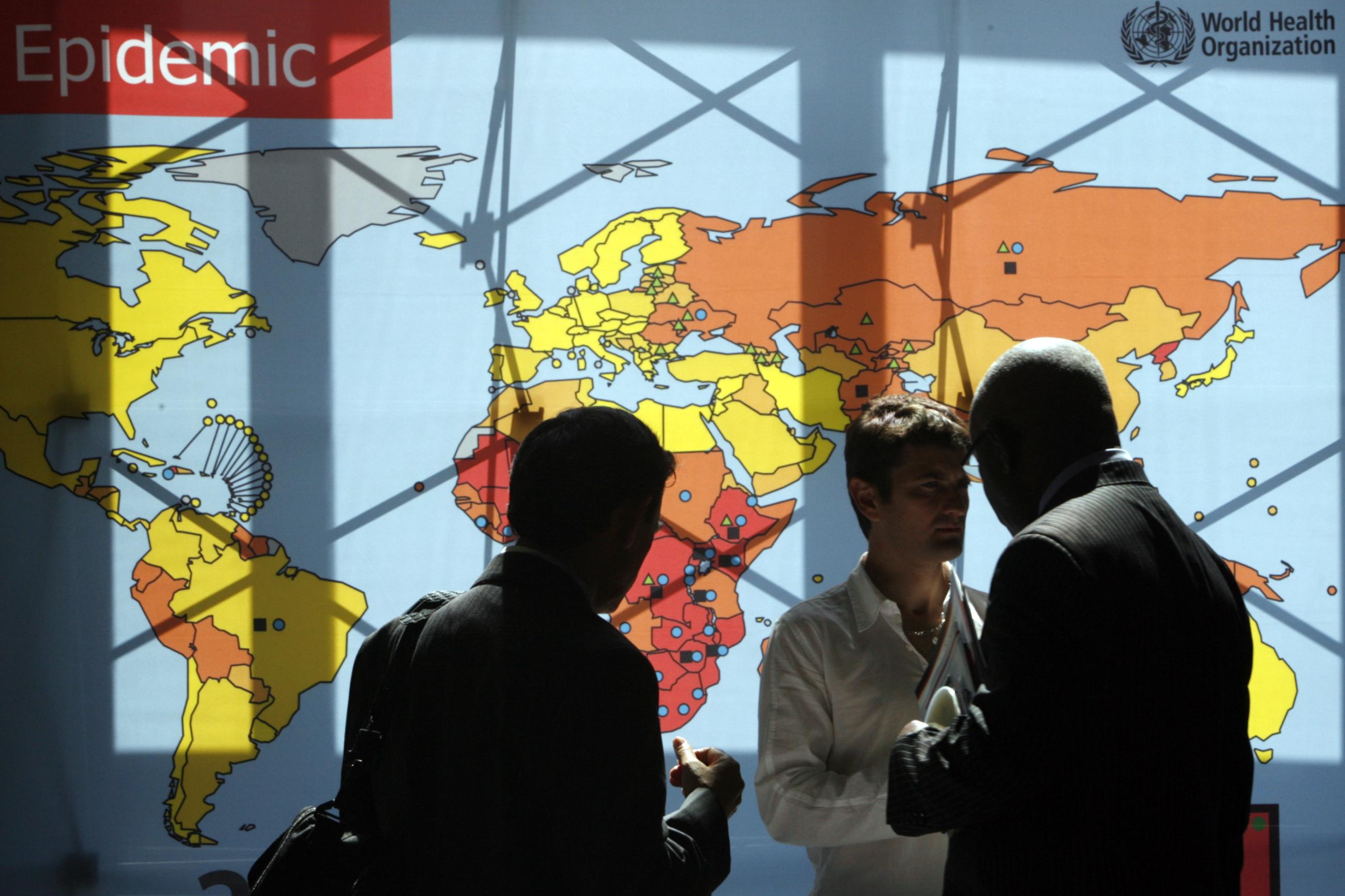 Delegates walk past an information board during the 62nd World Health Assembly at the United Nations European headquarters, in Geneva, Switzerland, on May 18, 2009.
