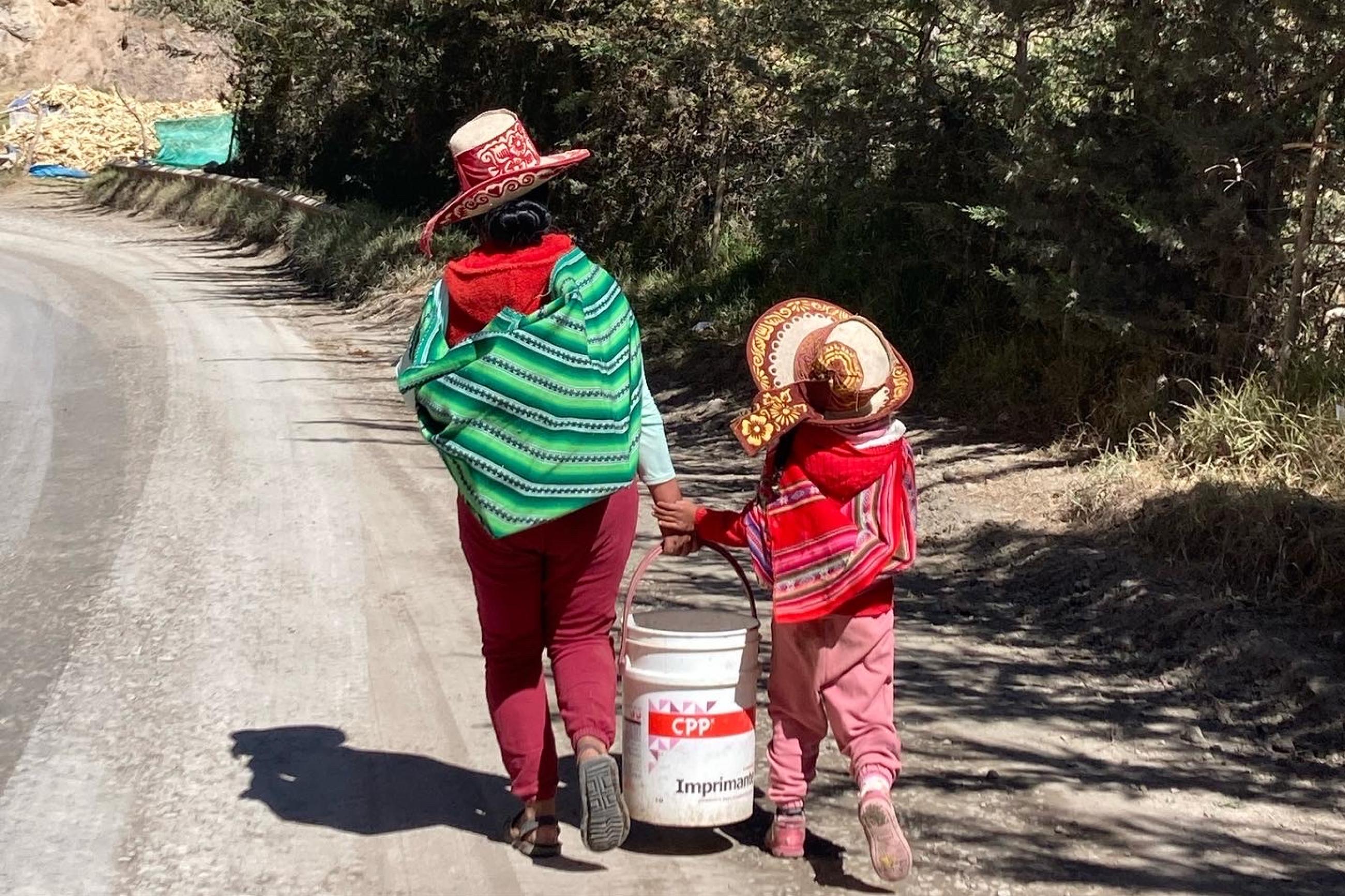 A mother and her daughter carry grain to their home in rural Cusco, Peru, on July 21, 2022