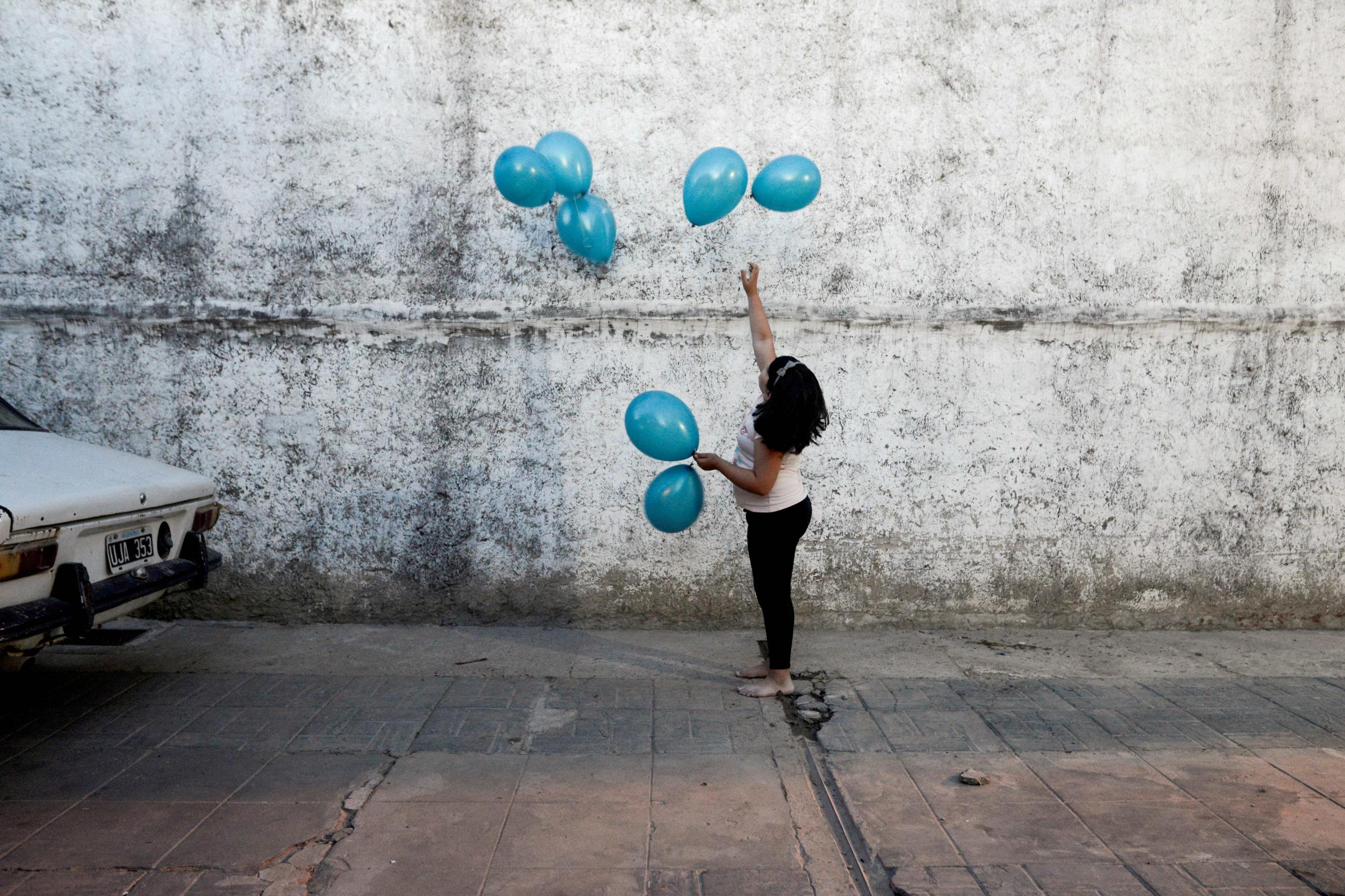 Michell, granddaughter of Rosalia Reyes who was sentenced to eight years in prison after her baby died during a home childbirth, plays with balloons during the welcome party for Rosalia after she was transferred home where she will serve the rest of her time under house arrest