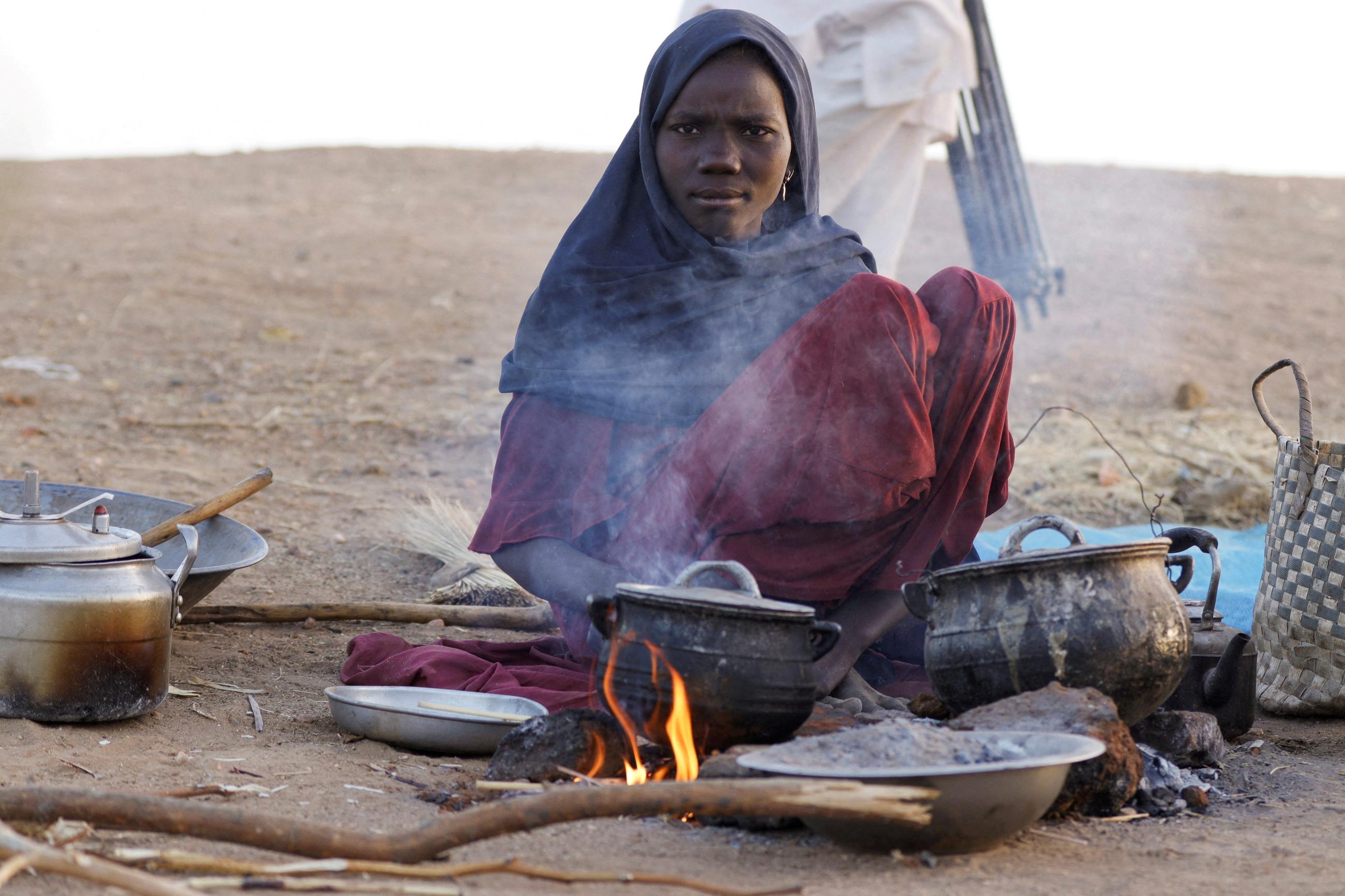 A displaced woman prepares food, following Rapid Support Forces attacks on Zamzam displacement camp, as she shelters in the town of Tawila, in North Darfur, Sudan, on April 16, 2025.