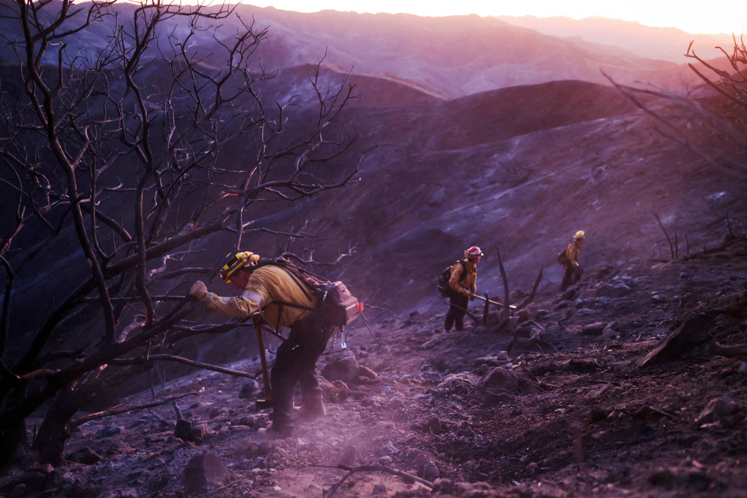 Members of a CalFire crew work to mop up hotspots from the burn scar of the Palisades Fire near Mulholland Drive in Los Angeles, California, U.S., January 15, 2025.