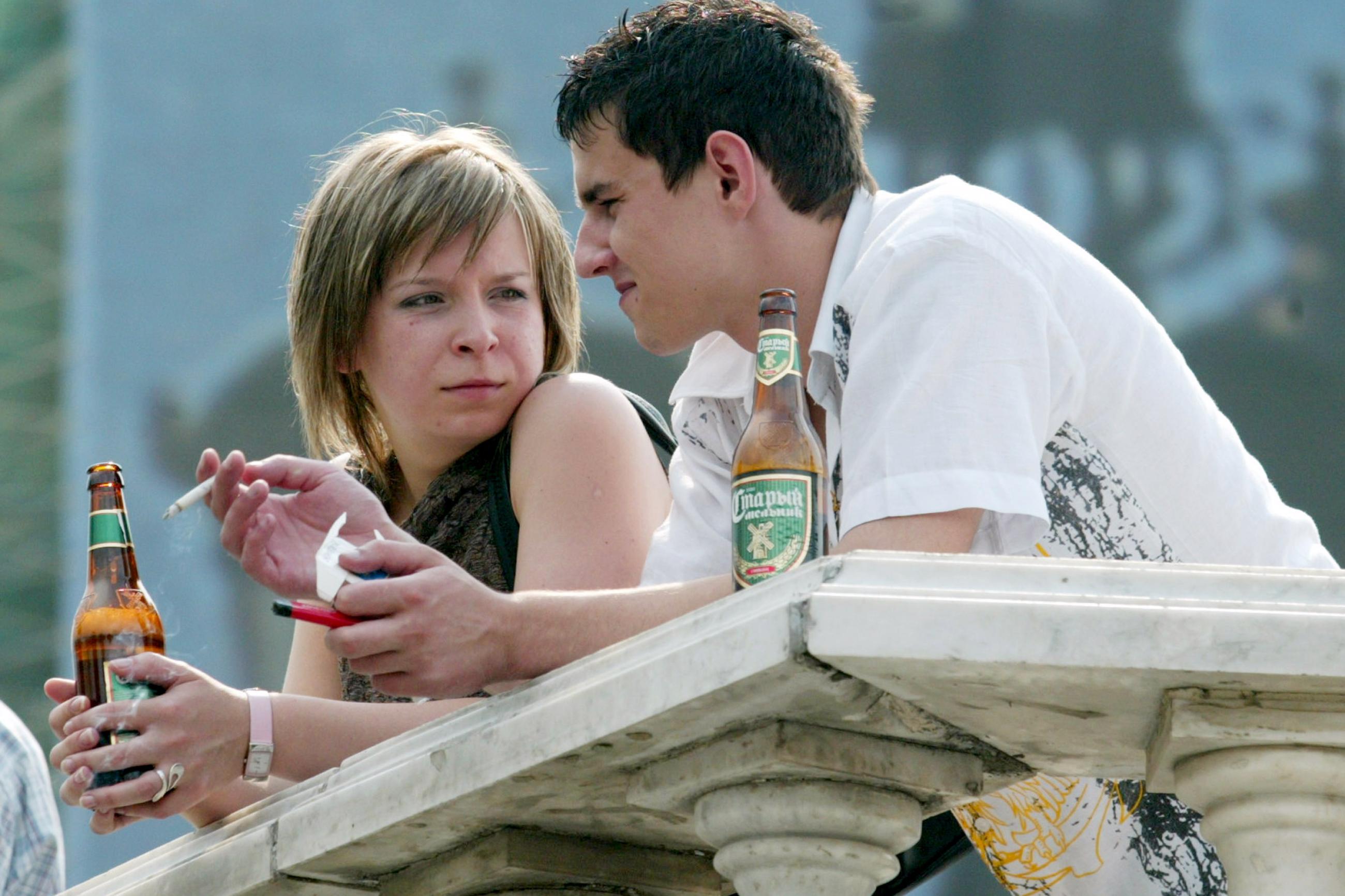 A young couple chat as they drink beer and smoke cigarettes, in Moscow, Russia, on August 8, 2004.