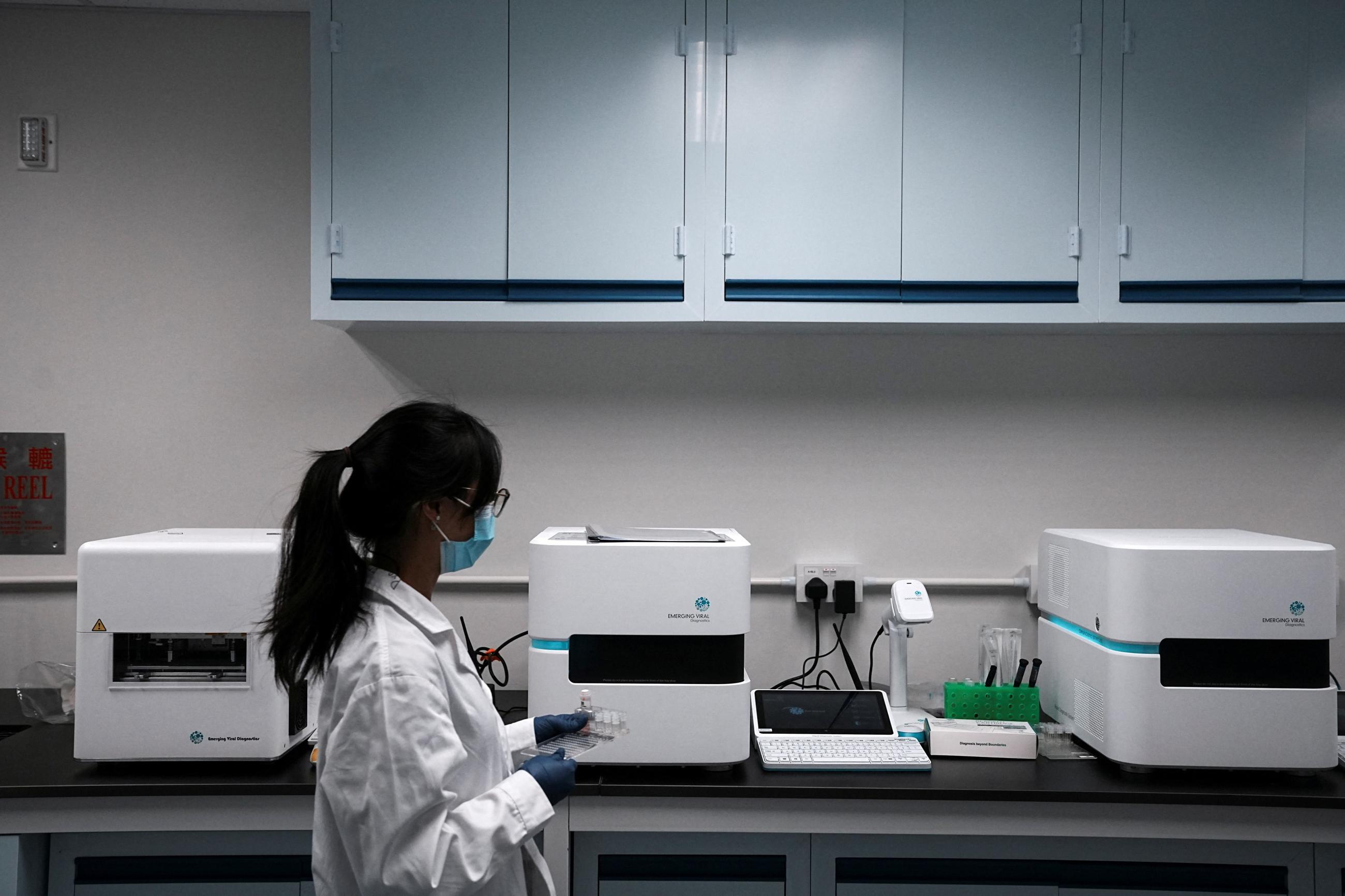 A staff member walks past the machines used for pathogen detection, at a laboratory inside the Emerging Viral Diagnostics office, in Hong Kong, China, on March 13, 2023.