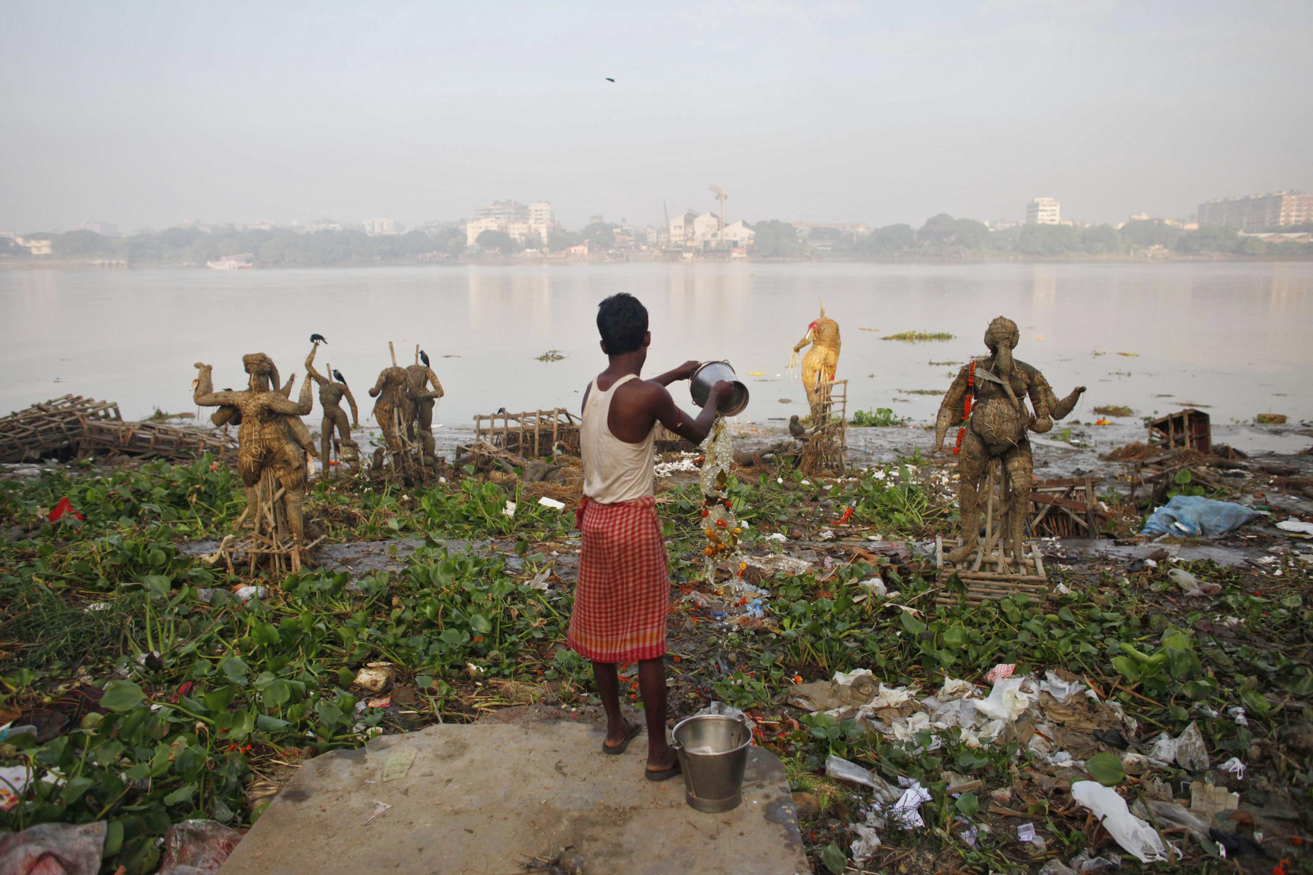 A man pours water on the polluted banks of river Ganges, in Kolkata, India, on October 20, 2010. 