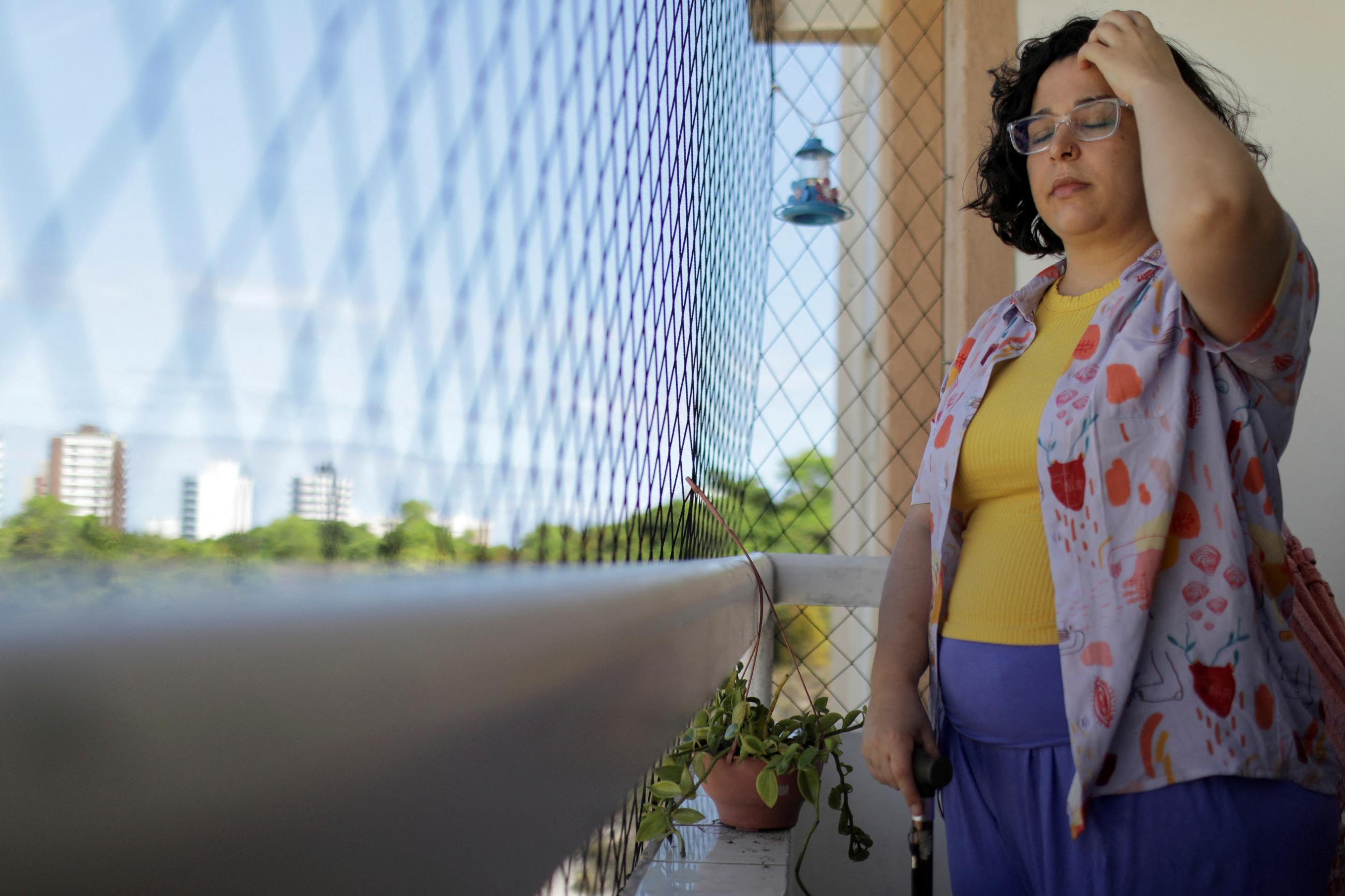 Leticia de Souza Soares, who suffers from pain and health problems caused by long COVID-19, stands on the balcony of her home, in Salvador, Brazil, on December 8, 2023. 
