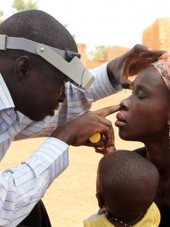 Technician doing eye exam during azithromycin mass drug administration training exercise near Ouagadougou, Burkina Faso.