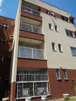 An apartment in the large urban center of Manaus, Brazil, showing a plain building with orange-beige and buttercream accents against a brilliant blue sky