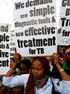 Demonstrators march through the streets of Cape Town to highlight the need for new strategies and medicines to curb the spread of tuberculosis on November 8, 2007. The picture shows a woman with red hair holding a sign above her head.