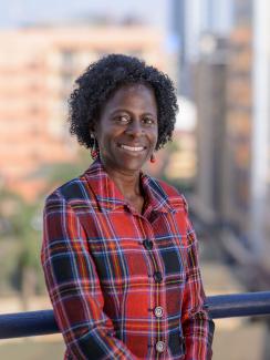 Picture shows Olive Kobusingye, Executive Director, Injury Control Center at Makerere Medical School in Kampala, Uganda. She is looking at the camera against a bright, blurred out background wearing a red-and-blue shirt in this posed shot. 