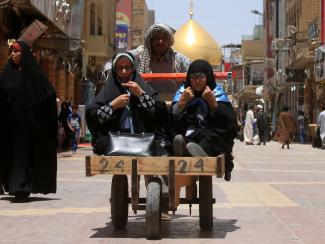 A man pushes a cart to transport women in Najaf, Iraq.