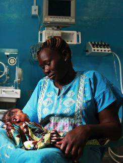  Photo shows a woman looking adoringly on her baby, who rests in her lap. 