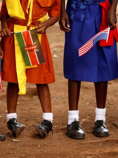 The photo shows four girls from the stomach down holding flags. 