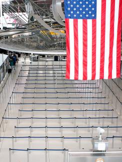 The picture is taken of a TSA checkpoint pavilion from a high vantage and shows a long snaking rope line completely empty of travelers. 