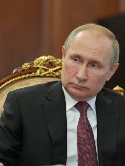 The picture shows Putin sitting in a chair listening. 