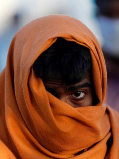 The image is very striking showing the man with a large wrap around his head and mouth against a creamy, out of focus, colorful background. 