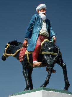 Photo shows a statue of the famous figure riding backward on a donkey. 