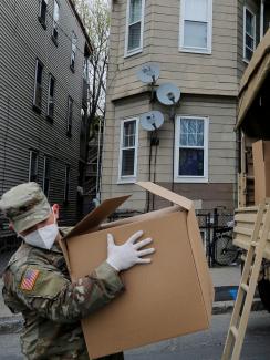 The photo shows a soldier wearing a mask with what looks like a heavy box on their shoulder. 