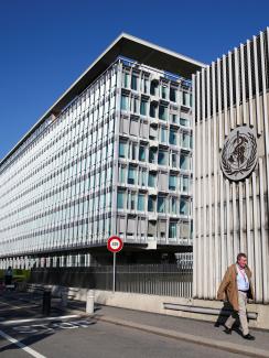 The photo shows the buildings with the official in front on a brilliant spring day with a clear blue sky. 