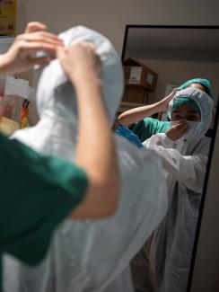 Picture shows a nurse being helped into her PPE. 