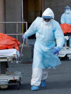  The photo shows two people in blue protective suits wheeling people away from a hospital entrance. REUTERS/Andrew Kelly