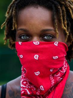  The photo shows a woman with a red bandana tied around her face. 