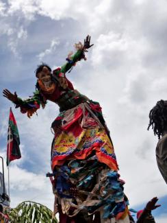 The photo shows a man in a stilt costume dancing. This is a striking photo. 