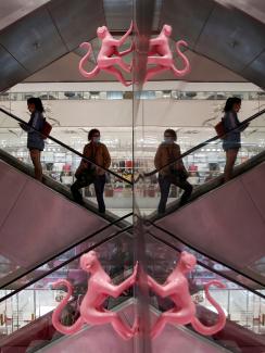 The photo shows people on an escalator with the photo showing mirror images on the left and right of the frame. 