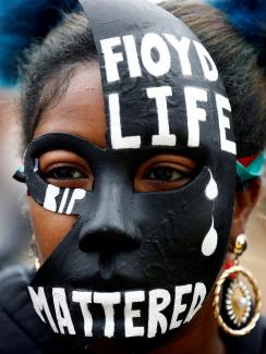 The picture shows a woman in a striking mask adorned with the words Floyd's Life "Mattered." 