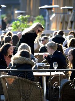 The photo shows a large number of people sitting close together in an outdoor eating area. 