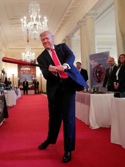 The photo shows the president hamming it up with people staffing booths and swinging a red bat. 