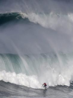 The photo shows a brave surfer in front of a massive towering wave. 