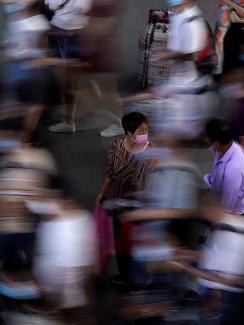 Picture shows a bustling crowd, all blurred as they move about, with one or two people standing still. 