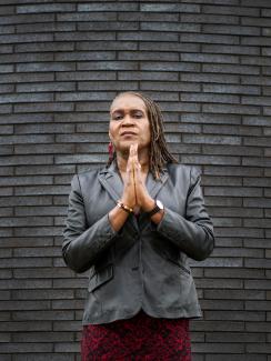 The photo shows the council vice president standing in front of a slate-colored brick wall with her hands together looking at the camera. 