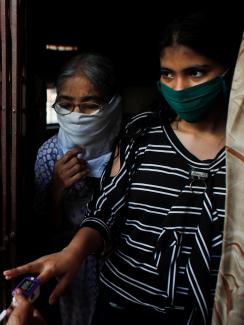 Community health volunteers check the pulse of a resident during a check-up campaign for COVID-19 in Mumbai, India.