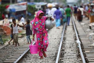 A slum dweller woman carries drinking water in Dhaka, Bangladesh, September 15, 2020. REUTERS/Mohammad Ponir Hossain