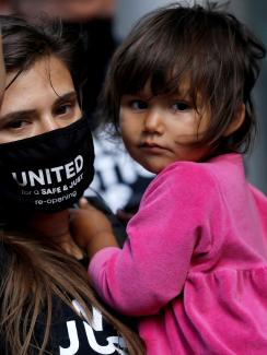 The photo shows a restaurant worker protesting while holding a small child. 