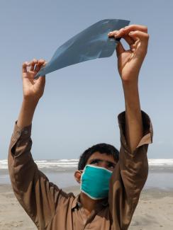 A boy holds an x-ray sheet as he observes the partial solar eclipse along Clifton beach, as the spread of the coronavirus disease (COVID-19) continues, in Karachi, Pakistan June 21, 2020.